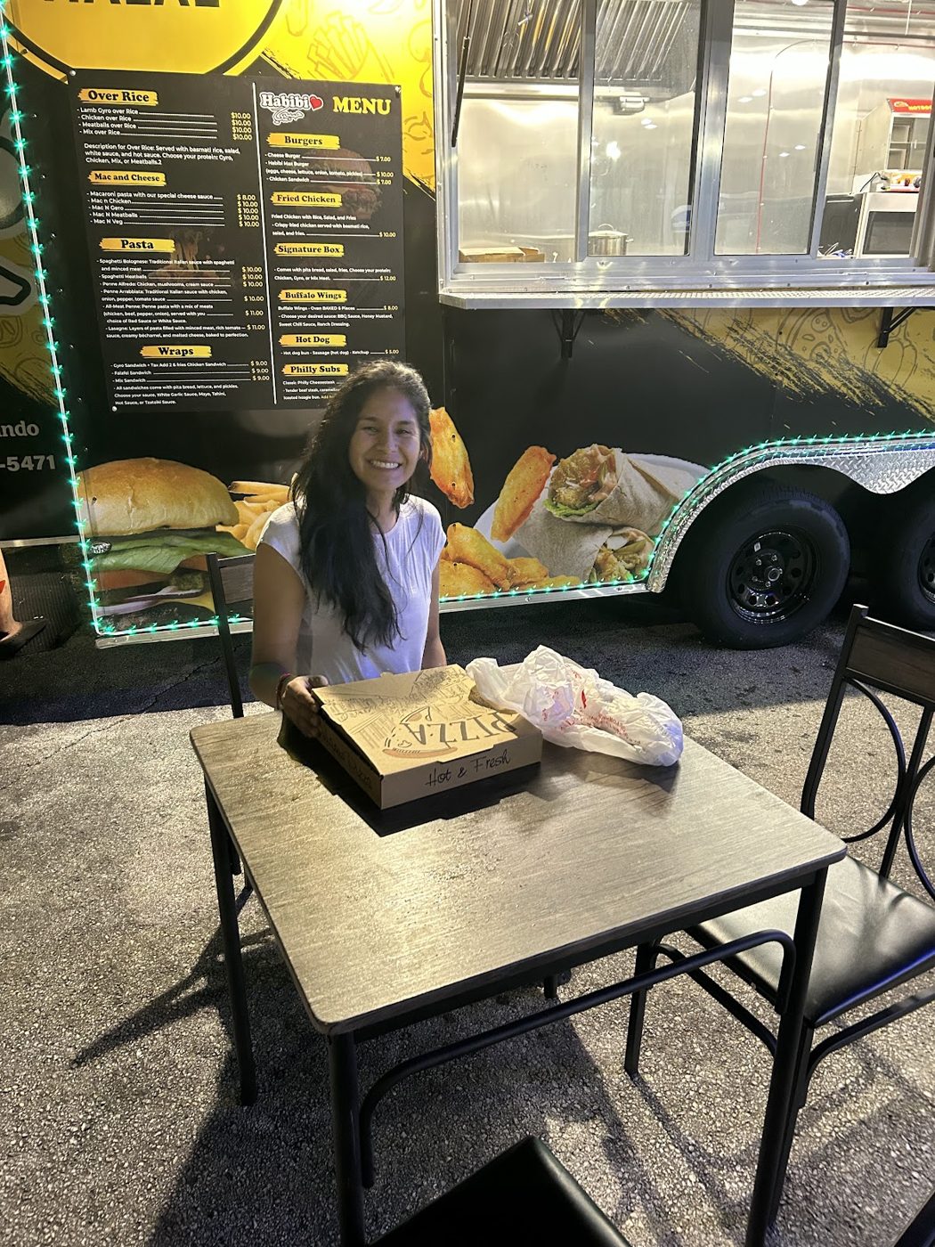 A regular enjoying a meal at the Habibi truck under the menu board