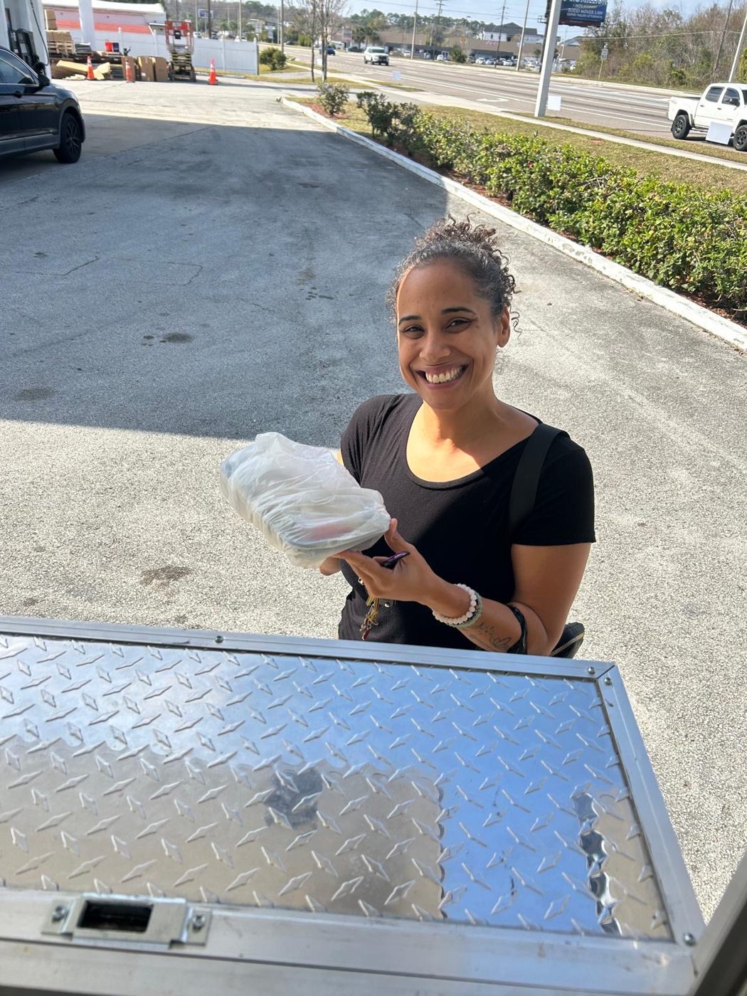 A happy Habibi customer picking up her order at the truck window