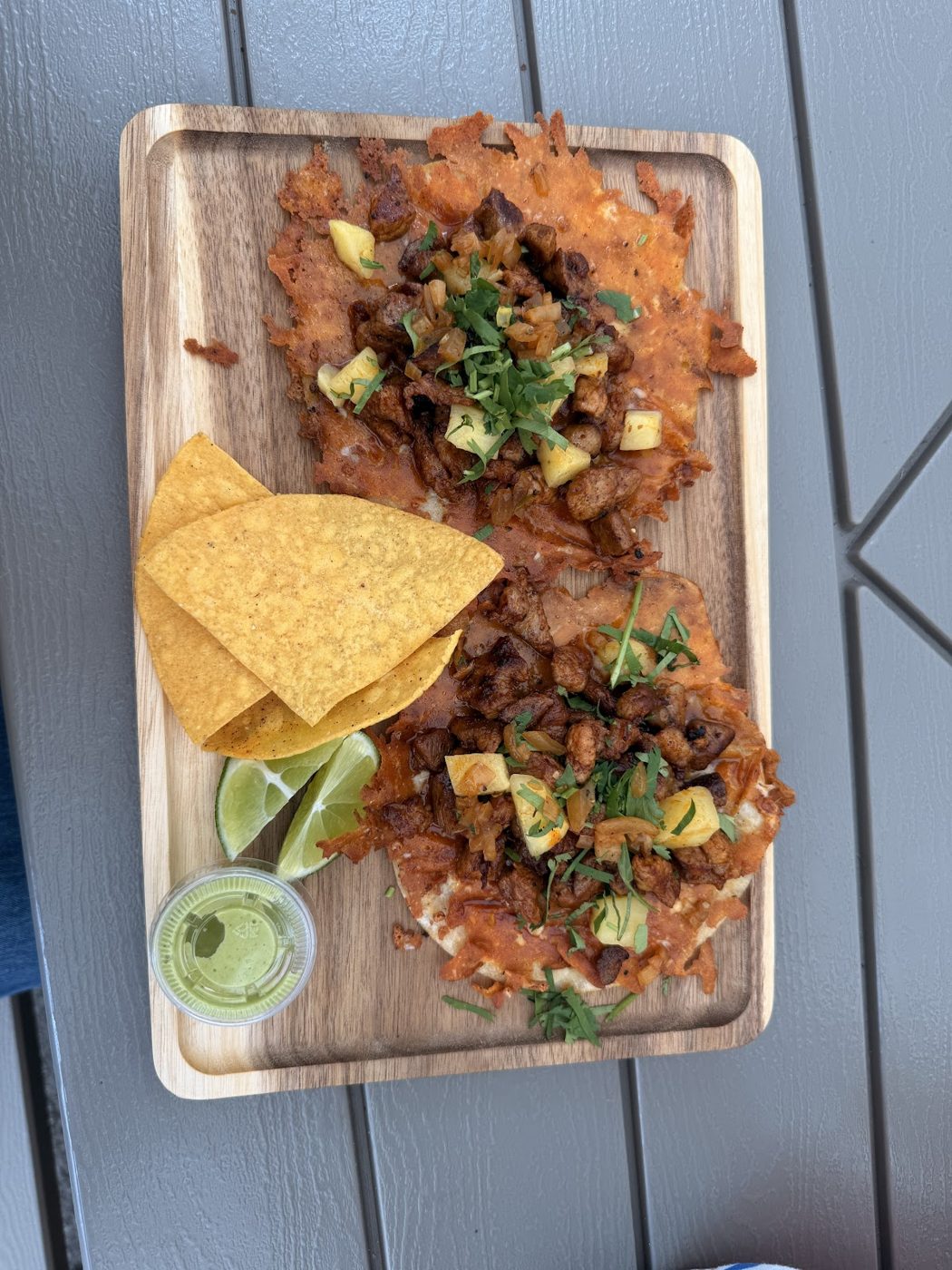 Al pastor tacos with pineapple, cilantro and crusted cheese on a wooden board